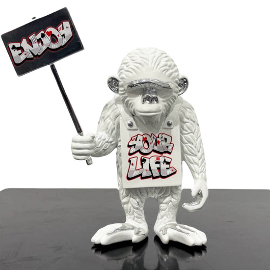 Sculpture of an white monkey with white Enjoy Your Life sign and crown